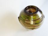 a brown and green vase sitting on a white surface