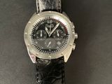 the watch is on a black leather strap on the table