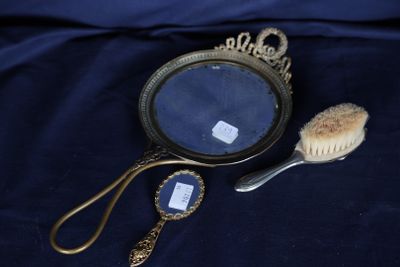 une photo représentant un miroir et une brosse posés sur un lit
