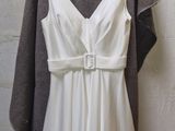 a white dress hanging on a hanger against a brick wall