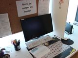 a desk with a computer, keyboard, mouse, and papers on it