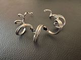 bracelet plaqué argent avec un motif en spirale sur une surface en cuir noir