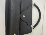 a black handbag hanging on a wall with gold hardware