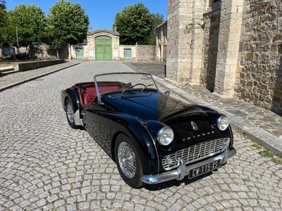 une voiture noire et rouge garée dans une rue pavée