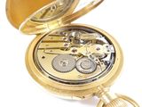a gold pocket watch that is open on a white surface