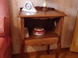 une petite table sur laquelle se trouve une horloge, à côté d'un lit