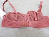 pink bralet with zippers on a bed with a tag on it