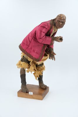 statue d'un homme vêtu d'un manteau rose, posée sur un socle en bois
