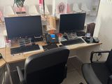 a desk with two computers and a chair in front of it