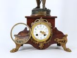 a clock with a statue of a man holding a magnifying glass in front of it