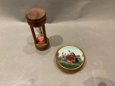 un petit sablier orné d'une image miniature, à côté d'un autre petit sablier