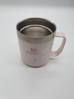 une tasse rose avec une anse, posée sur une table blanche