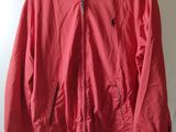 une veste rouge suspendue à un cintre devant un mur blanc
