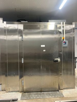 Plusieurs boxes en acier inoxydable sont alignés dans une grande pièce