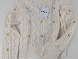 a close up of a white sweater with a tag on it
