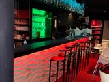 un bar avec un tapis rouge, des chaises et une lumière verte