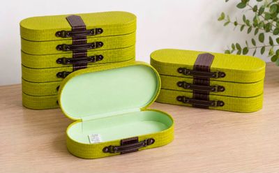 two green boxes with brown handles sitting on a wooden table