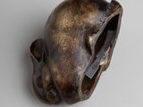 a small statue of a human head on a white surface