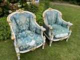 pair of blue and white chairs with gold trim in a garden