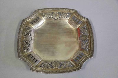une assiette en argent posée sur une table, sur fond blanc