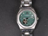 une montre en argent avec un cadran vert sur un fond noir