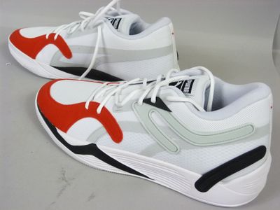une paire de baskets blanches rehaussées de touches rouges et noires, posée sur une table