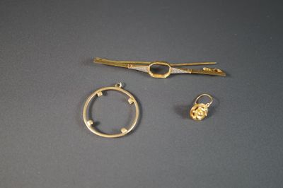 deux bijoux en or posés sur une surface grise