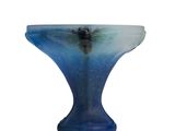 a blue glass bowl with a black base on a white surface