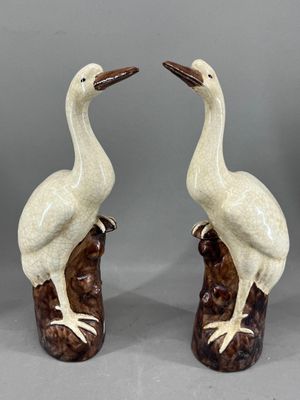 une paire d'oiseaux en céramique, l'un blanc et l'autre marron, perchés sur une souche d'arbre