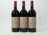 trois bouteilles de vin rouge posées l'une à côté de l'autre sur une surface blanche