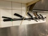 a lot of knives hanging on the wall in the kitchen