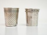 deux tasses en argent posées l'une à côté de l'autre sur une table