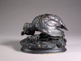 bronze sculpture of a bird on a rock on a white surface