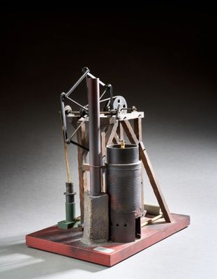 une vieille maquette de machine à vapeur posée sur un socle en bois