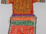 une robe brodée orange et verte accrochée à un mur