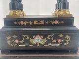 a black and gold clock with two candles on top of it