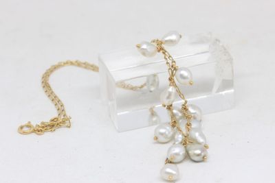 a necklace with pearls hanging from it on a clear box