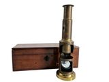 un vieux télescope en laiton dans un coffret en bois, sur fond blanc