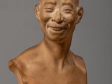 a close up of a clay bust of a man with a smile on his face