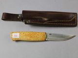 a knife that is sitting next to a leather sheath