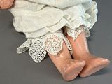 a doll that is sitting on the floor wearing a white dress