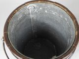 a metal bucket with a handle on a white surface