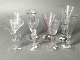 six wine glasses are lined up in a row on a gray surface
