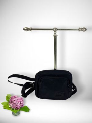 a black bag hanging on a wall next to a pink flower