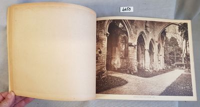 an old photo of a person holding a book open to a picture of a building