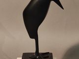 statue of a black bird on a white base on a gray background