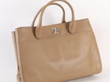 beige leather handbag on a white background with a silver handle