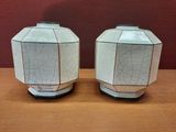 deux vases blancs posés sur une table en bois, avec un mur rouge en arrière-plan