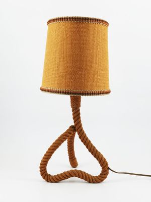 La lampe est fabriquée en corde et possède un abat-jour marron.