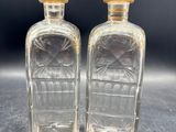 deux bouteilles en verre transparent ornées d'étoiles dorées sur le goulot